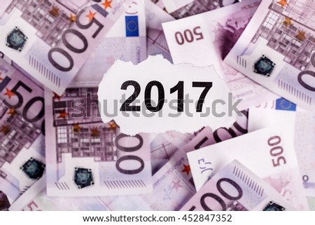Focus on the words 2017  on piece of torn white paper with EURO currency as a background. Concepts of investment and business.