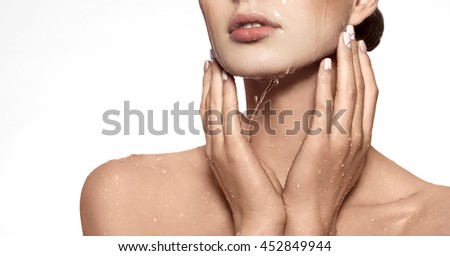 Beautiful Model Girl with splashes of water in her hands. Beautiful Smiling Woman under splash of water with fresh skin over white background. Skin care Cleansing and moisturizing concept. Beauty face Royalty-Free Stock Photo #452849944