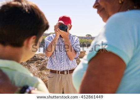 Happy tourists on holidays. Hispanic people traveling in Havana, Cuba. Grandfather, grandmother and grandchild during summer travel, with senior man taking photos with camera