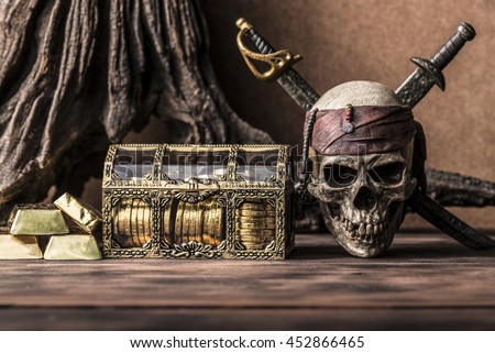 still life photography with pirate skull holding two swords and treasure coffer, gold bar,  bullion. Halloween concept