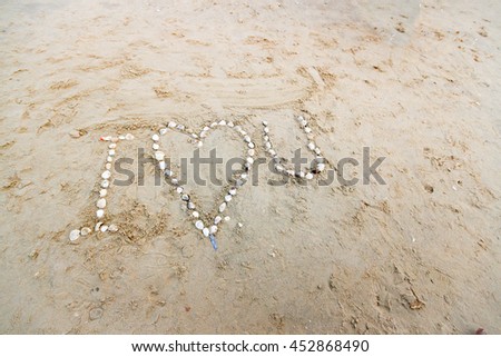 "I love U"words by shell on sand before sunset