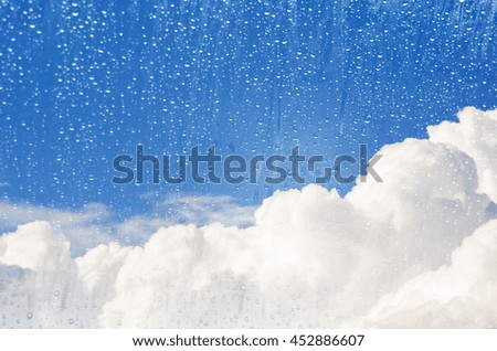 blue sky and clouds with rain drops in glass