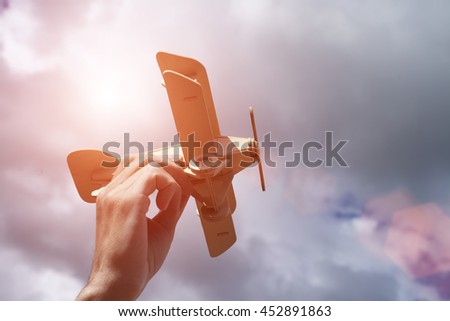 A hand with wooden airplane against the sky. Instagram effect, toned photo filter