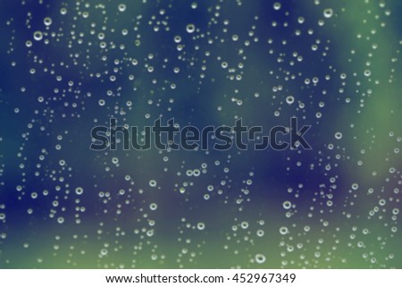 Drops of Rain on Glass window blurred forest background, vintage color tone.