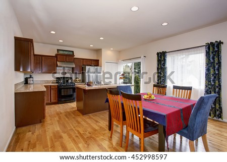 Bright kitchen and dining room interior with white walls, colorful curtains and hardwood floor.