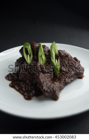 A malay dish called 'masak hitam' serve in a plate. Selective focus, shallow depth of field. Dark background