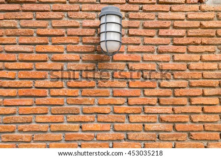 Clean bright orange brick wall with plastic lamp on the middle top of the photo - lighting is from top right side - background with empty space for additional text
