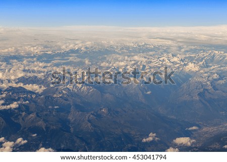 Heavenly landscape. A view of white clouds and the massif lit the sun from a window of the flying plane