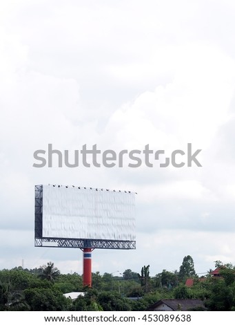 large scale empty blank billboard with blue red painted pole without advertisement surrounding with green environment blue sky white cloud with rooms for your text both on the board and on the sky