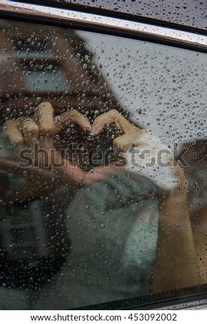 Silhouette of hands against the background of a window in the form of heart