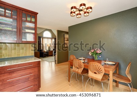 Served dining table decorated with fresh flowers. Interior design of dining room with deep green wall.