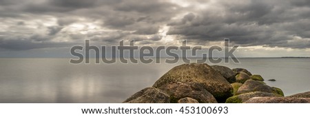 Beautiful coastal scenery, stones and sandy beach under a cloudy sky, relax and chill, panorama
