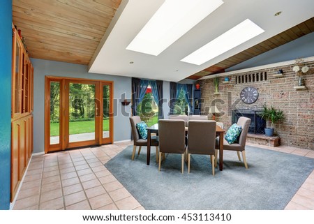 Light spacious dining room with stone tile wall and built-in fireplace, skylight, tile flooring and view of back yard.