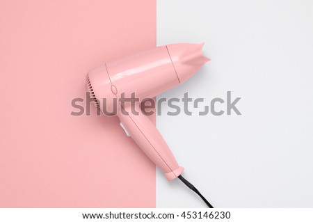Pink hair dryer on pink and white paper background Royalty-Free Stock Photo #453146230