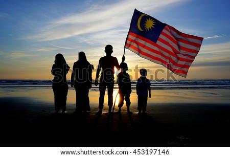 Silhouette of family with waving a Malaysian flag at beach. independence day / merdeka day.