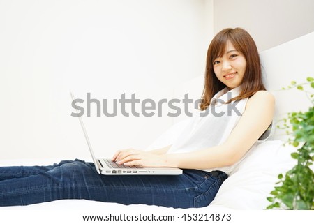Young Japanese woman using computer on the bed
