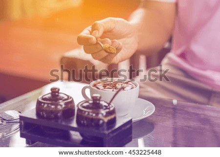 Closeup of a cropped man pouring sugar into coffee cup