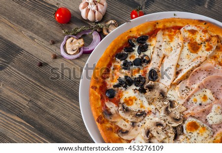 Pizza "Four Seasons" with ham, mushroom, meat, olive on wood table