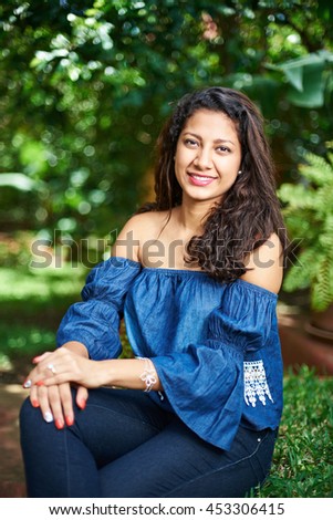 young latina girl sit in park with blurred background