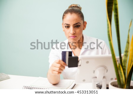Female therapist and cashier swiping a credit card and processing a payment at a health and beauty spa