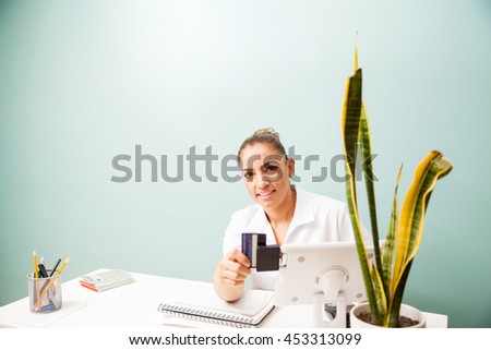 Portrait of a female cashier at a business front desk swiping a credit card in a reader and smiling