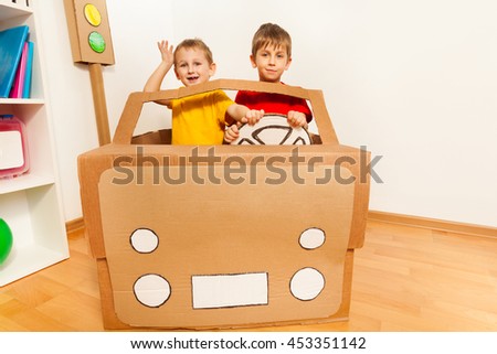 Two boys driving toy handmade cardboard car