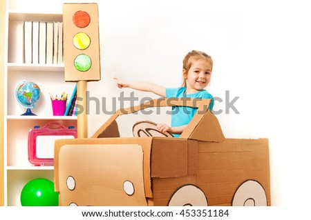 Little girl at the wheel of handmade cardboard car
