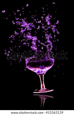 Blue cocktail glass splash out on a black background.
