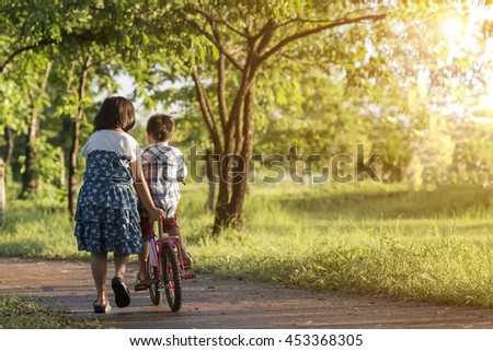 Sister learn his little son lessons bicycle riding.