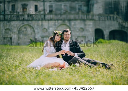 Wedding couple picnic on the grass in the front of an old castle