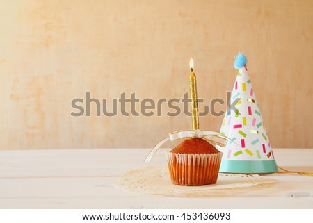 Birthday concept with cupcake and candle, party hat on wooden table