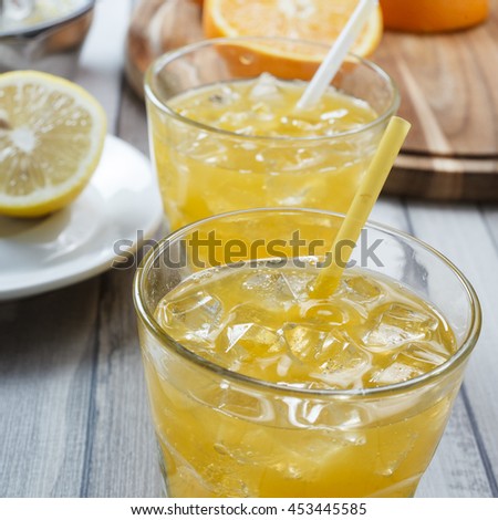 The cooled drink with fresh lemon and orange. On the table two glasses with a drink and fresh fruit