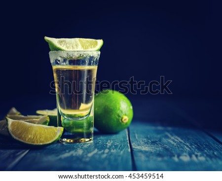 Mexican Gold Tequila with lime and salt on dark table. Toned. Retro style vintage color. Copyspace for text. Royalty-Free Stock Photo #453459514