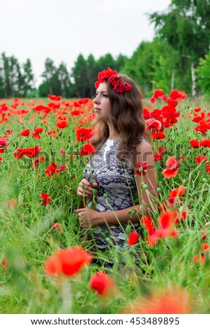 Beautiful happy smiling woman in red poppy field nature background. Attractive brunette young girl model with curly hair and makeup laughing at camera