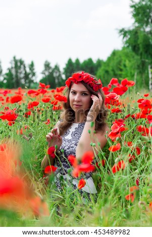 Beautiful happy smiling woman in red poppy field nature background. Attractive brunette young girl model with curly hair and makeup laughing at camera