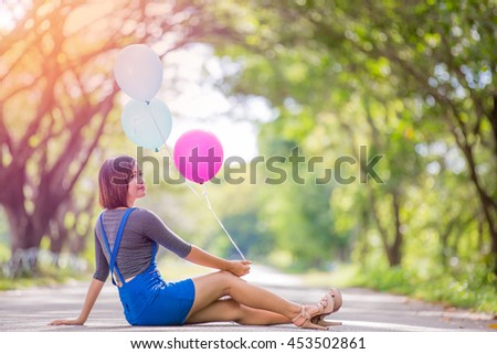 The girl with balloons plays on the road with sunshine