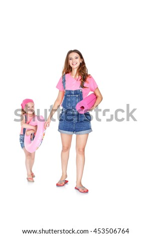 happy family going to the beach. beautiful mom and lovely daughter with a pink rubber ring and  beach Mat