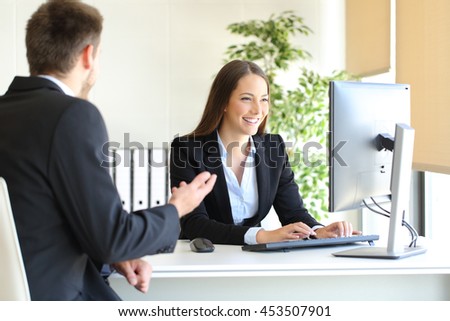Agent attending to a client introducing data in a desktop computer at office Royalty-Free Stock Photo #453507901