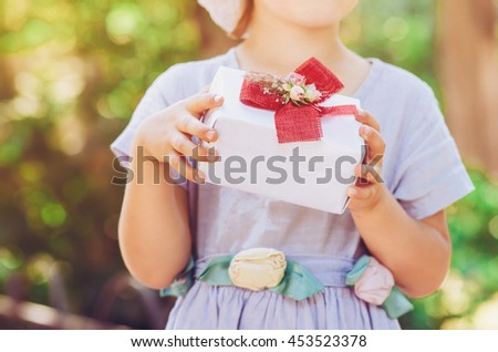 Beautiful little girl with gift box in a summer park 