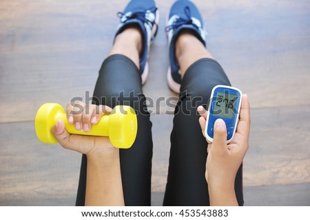 Girl holding dumbbell and glucose meter,concept for diabetes lifestyle and healthy. Royalty-Free Stock Photo #453543883