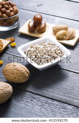 sun dried super foods, nuts and cereals on black wood table background