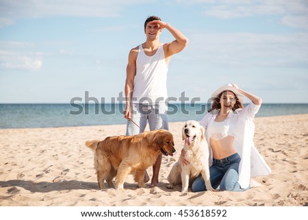 Romantic young beautiful couple standing on the sea shore with dog