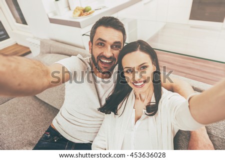Selfie fun. Top view of happy loving couple bonding to each other and making selfie while sitting on the couch together