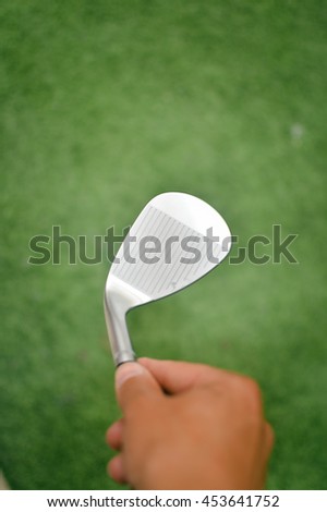 Choosing holding golf club in hand, close up view, defocused background