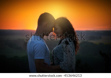 young couple at sunset on sky background, love concept, romantic people
