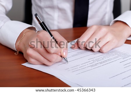 person's hand signing an important document