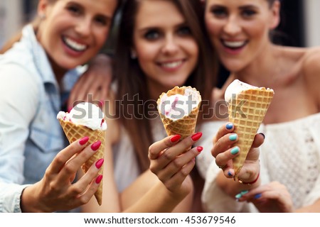 Picture presenting happy group of friends eating ice-cream outdoors