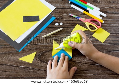 The child makes a book with a bookmark mignon. The child bonded items paper products. Glue, paper, scissors on a wooden table. Children's art project, a craft for children.