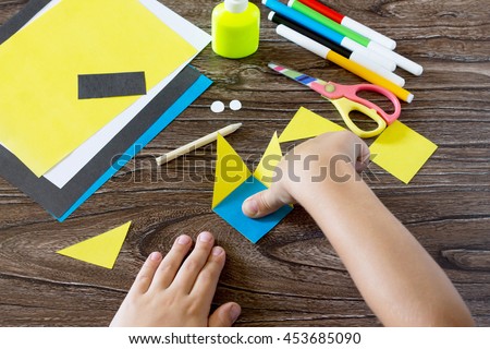 The child makes a book with a bookmark mignon. The child bonded items paper products. Glue, paper, scissors on a wooden table. Children's art project, a craft for children. Craft for kids.