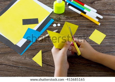The child makes a book with a bookmark mignon. The child carves the details of paper products. Glue, paper, scissors on a wooden table. Children's art project, a craft for children. Craft for kids.
